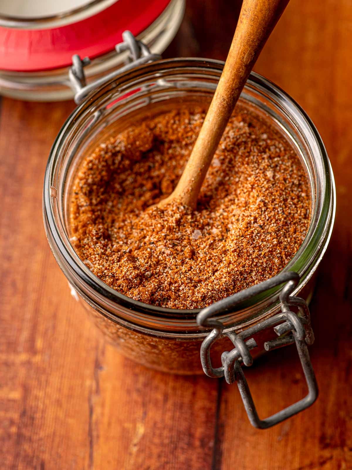 Overhead view of BBQ rub in a clamp jar with a wooden spoon, ready to use.