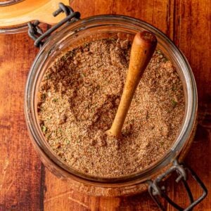 Jar filled with jerk seasoning blend, surrounded by warm wooden tones and rustic texture.