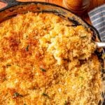 Serving shot of smoked mac and cheese in a skillet with crispy topping and fresh chives.