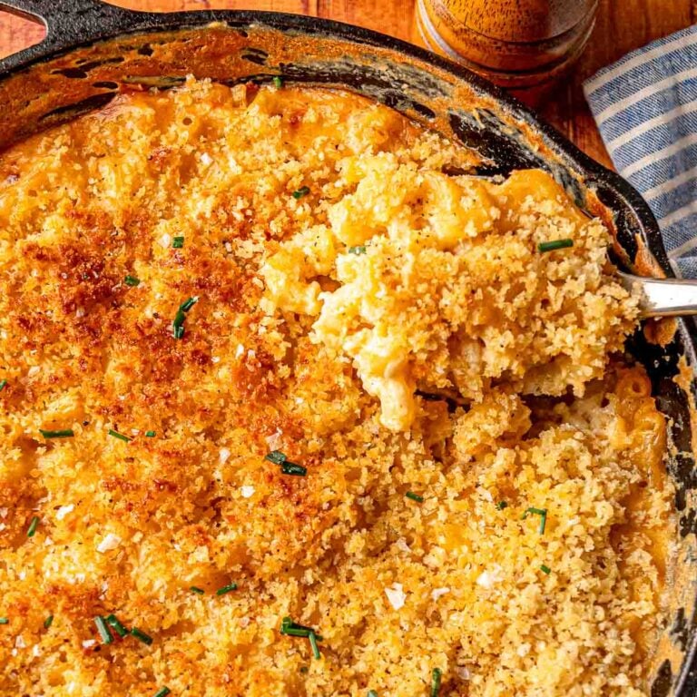 Serving shot of smoked mac and cheese in a skillet with crispy topping and fresh chives.