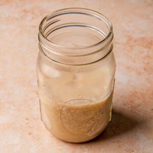 Rendered beef tallow in a glass jar with a spoon, showing smooth texture and creamy golden color.