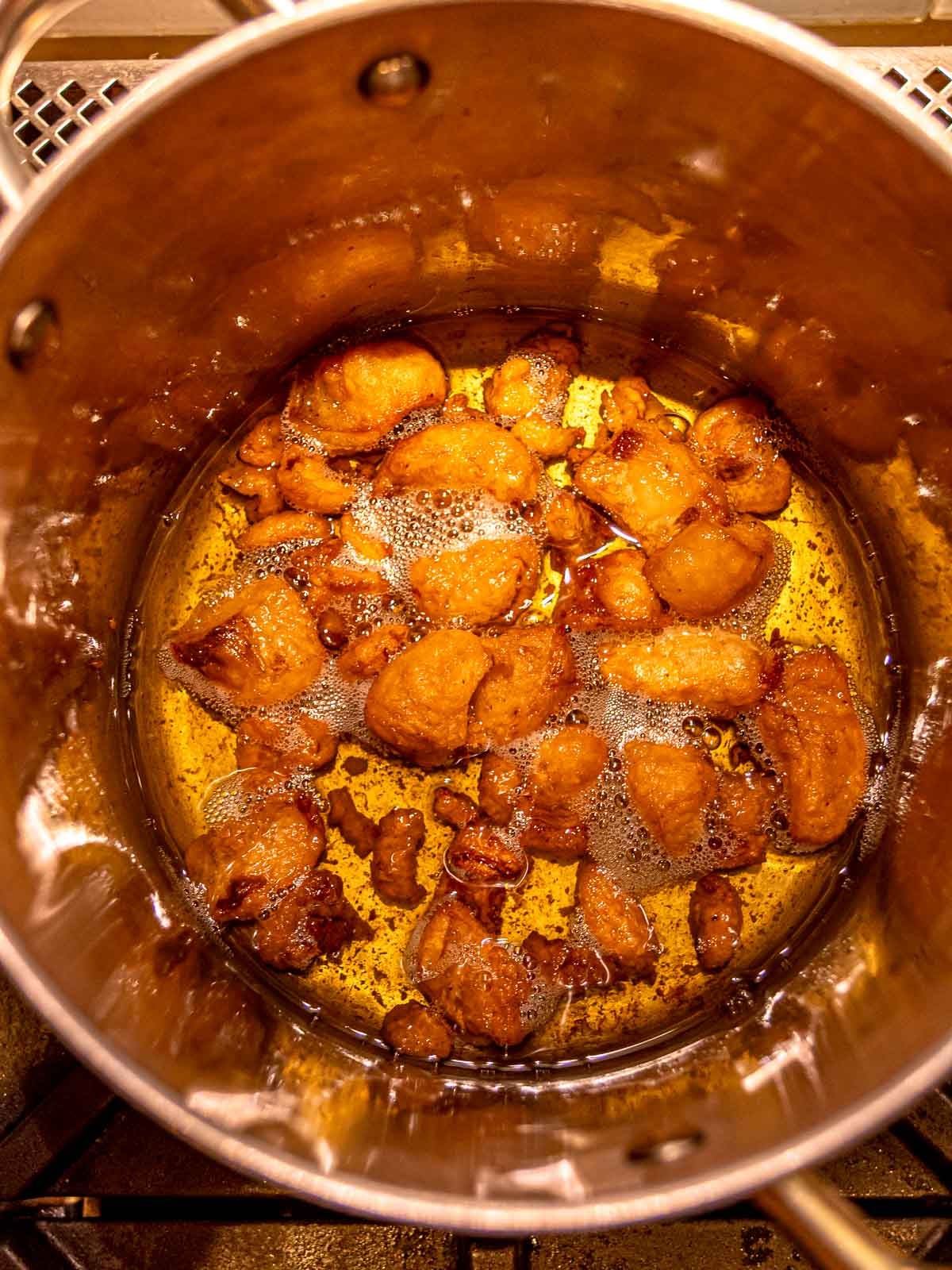 Golden liquid tallow simmering gently in a skillet as it renders from beef fat.