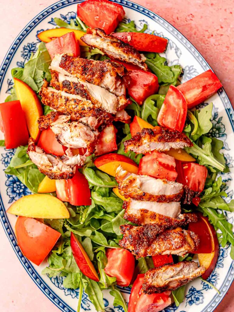 Sliced smoked BBQ chicken served over arugula with fresh peaches and tomatoes.