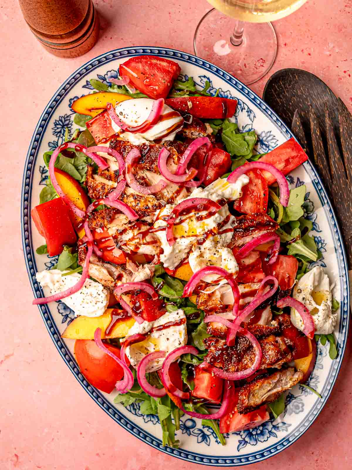 Colorful smoked BBQ chicken salad with burrata, red onions, and balsamic glaze ready to serve.