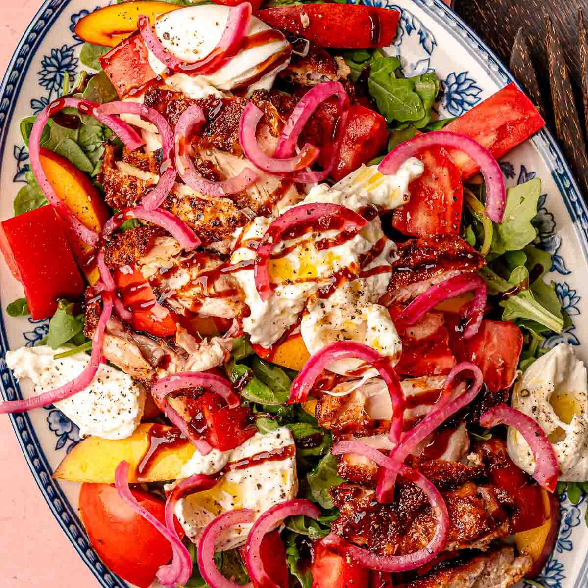 Smoked BBQ chicken salad with arugula, juicy peaches, fresh tomatoes, and creamy burrata.
