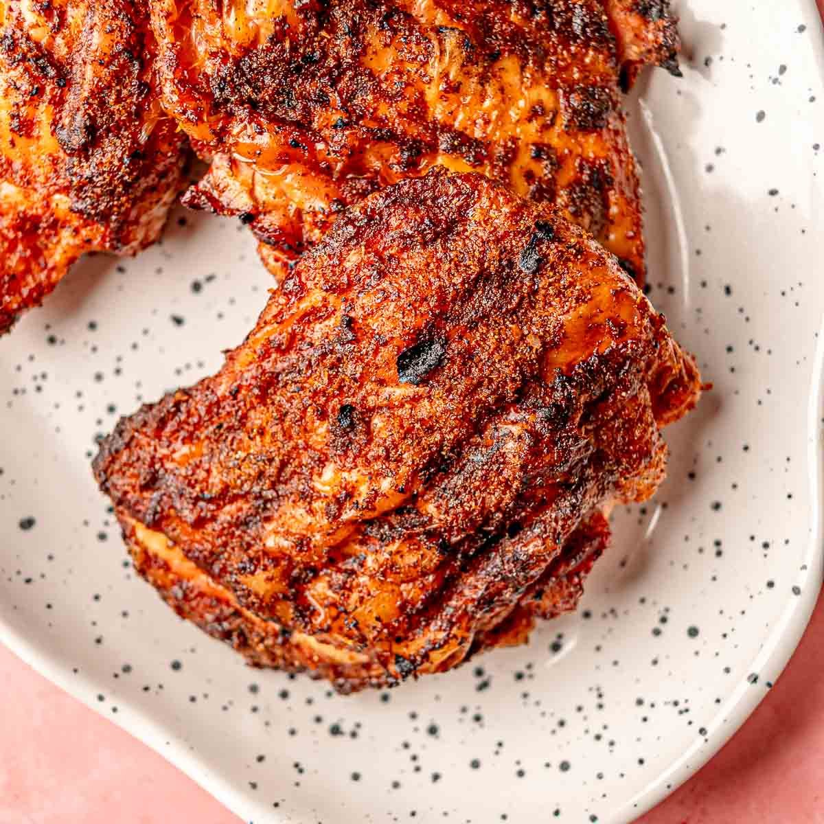 Smoked BBQ chicken thighs served on a platter.