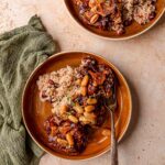 Plate of smoked oxtail with rice and peas, garnished with thyme sprigs.