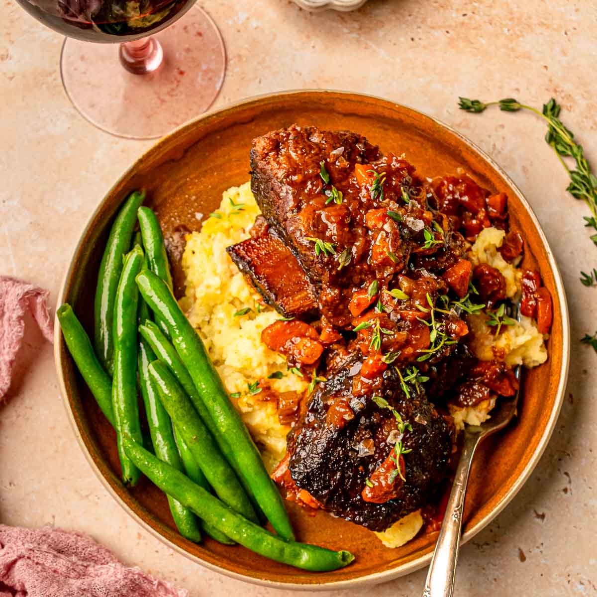 Smoked bone-in short rib with a peppery crust resting on grill grates.