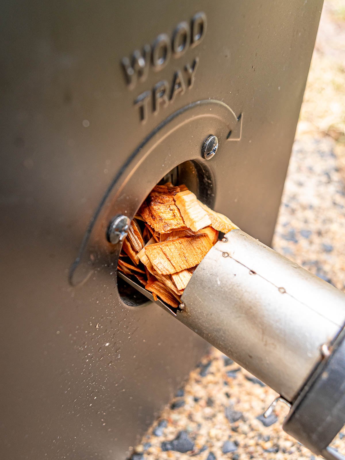 Wood chips loaded into the side tray of a Masterbuilt electric smoker.