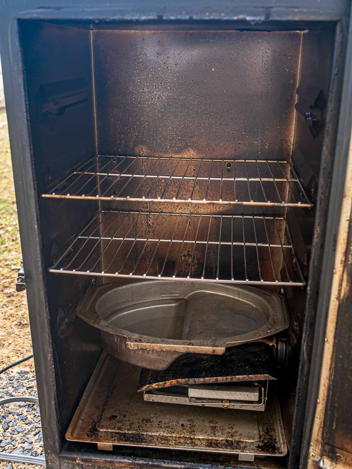 Inside of a Masterbuilt electric smoker with racks, water pan, and wood chip tray in place.