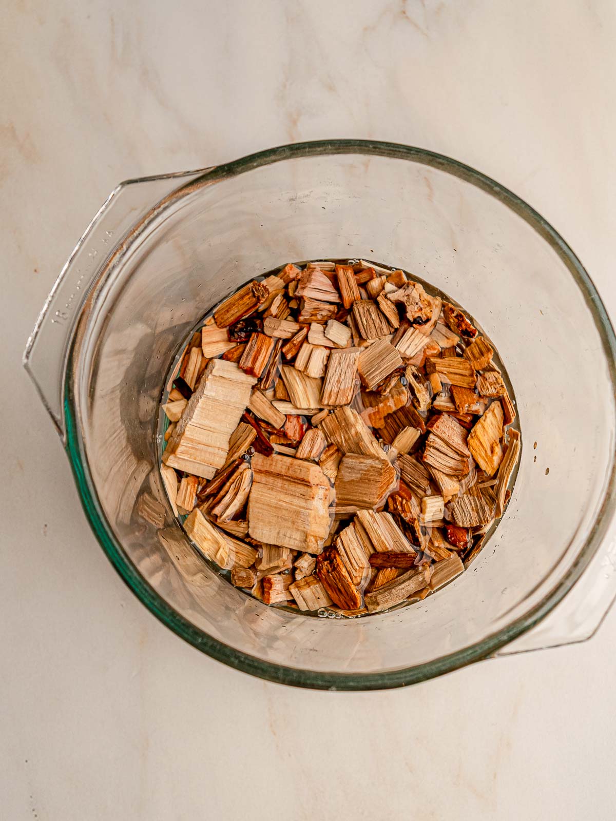 Wood chips soaking in water in a glass bowl.